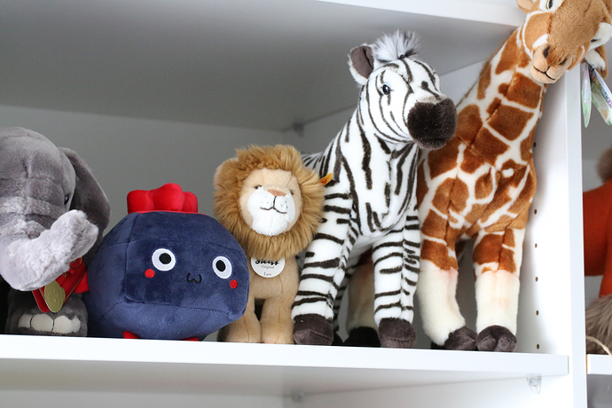 The plushie on a shelf with other stuffed animals.