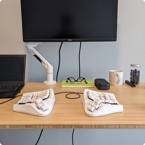 TAIKO 01 ergonomic keyboard in white on a standing desk with a Dell monitor in the back.